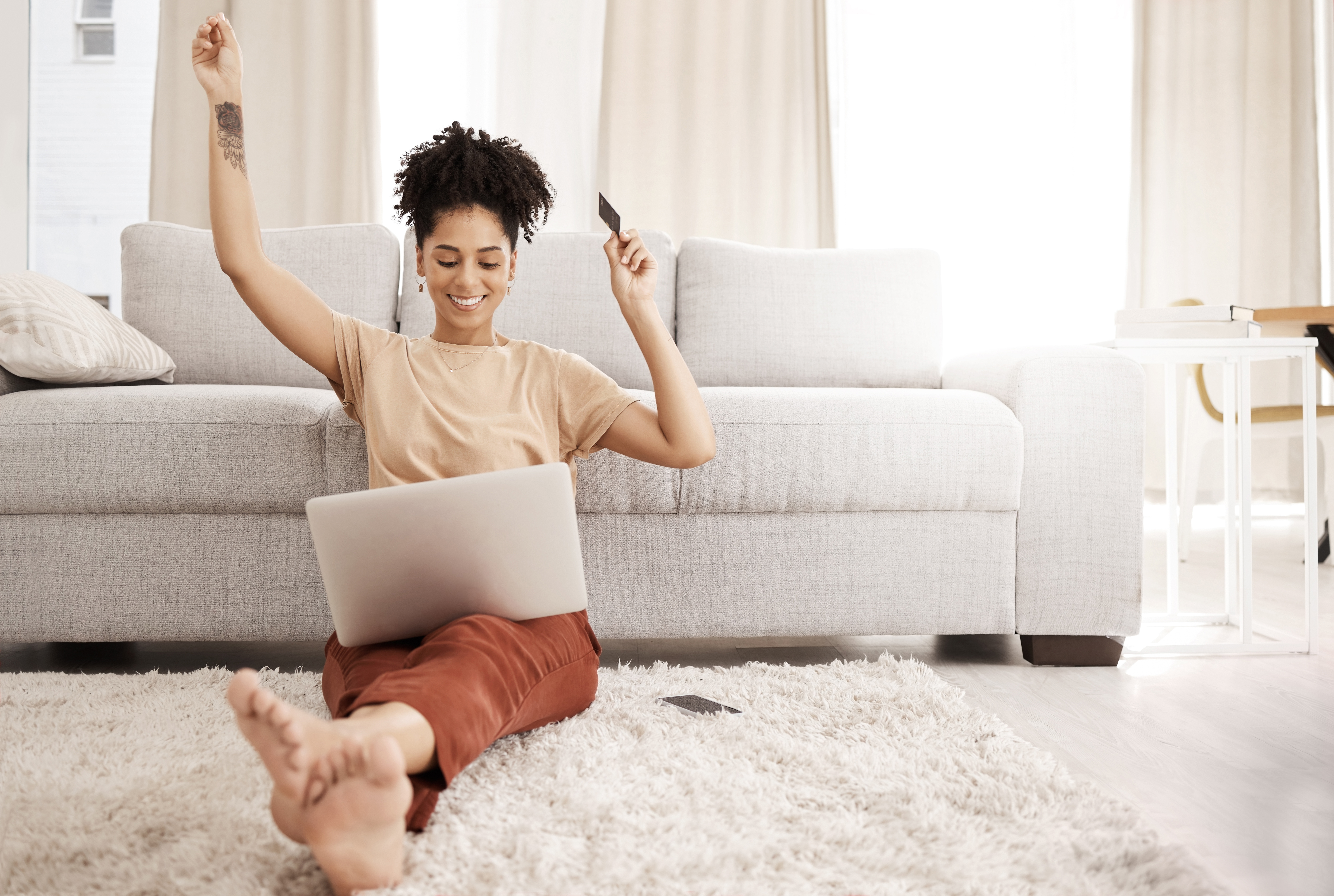 Black woman, laptop and happy with credit card, ecommerce and approved loan in lounge. Young female